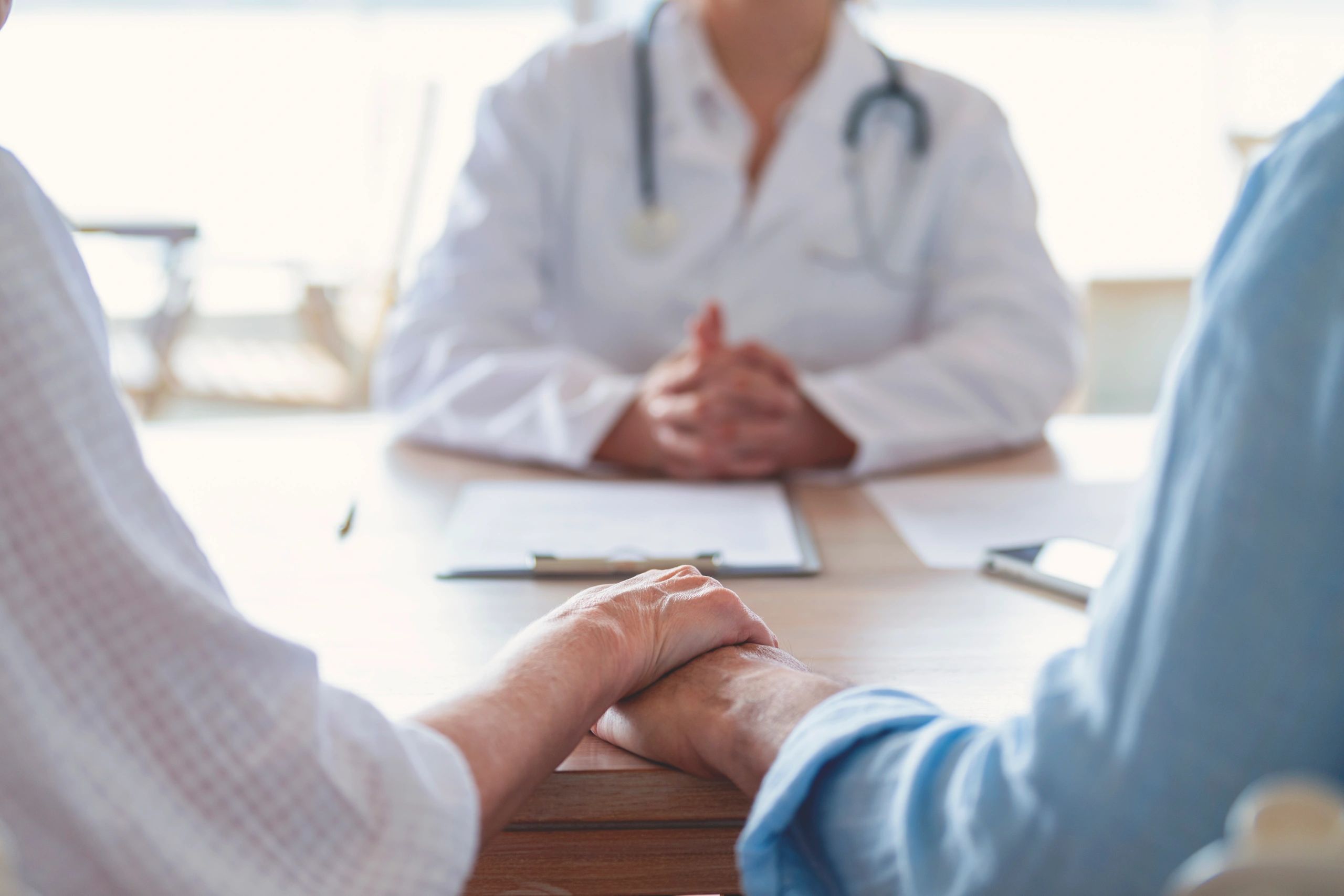 Mature couple holding hands during a doctor visit