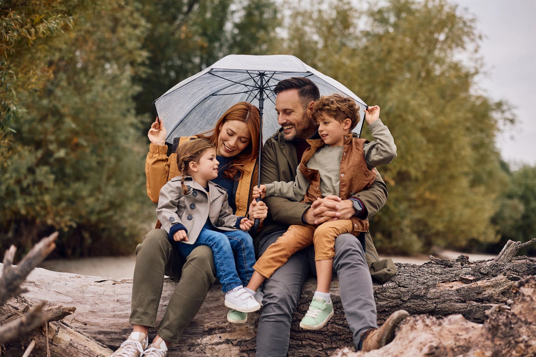 Parents and children sitting together under an umbrella outdoors